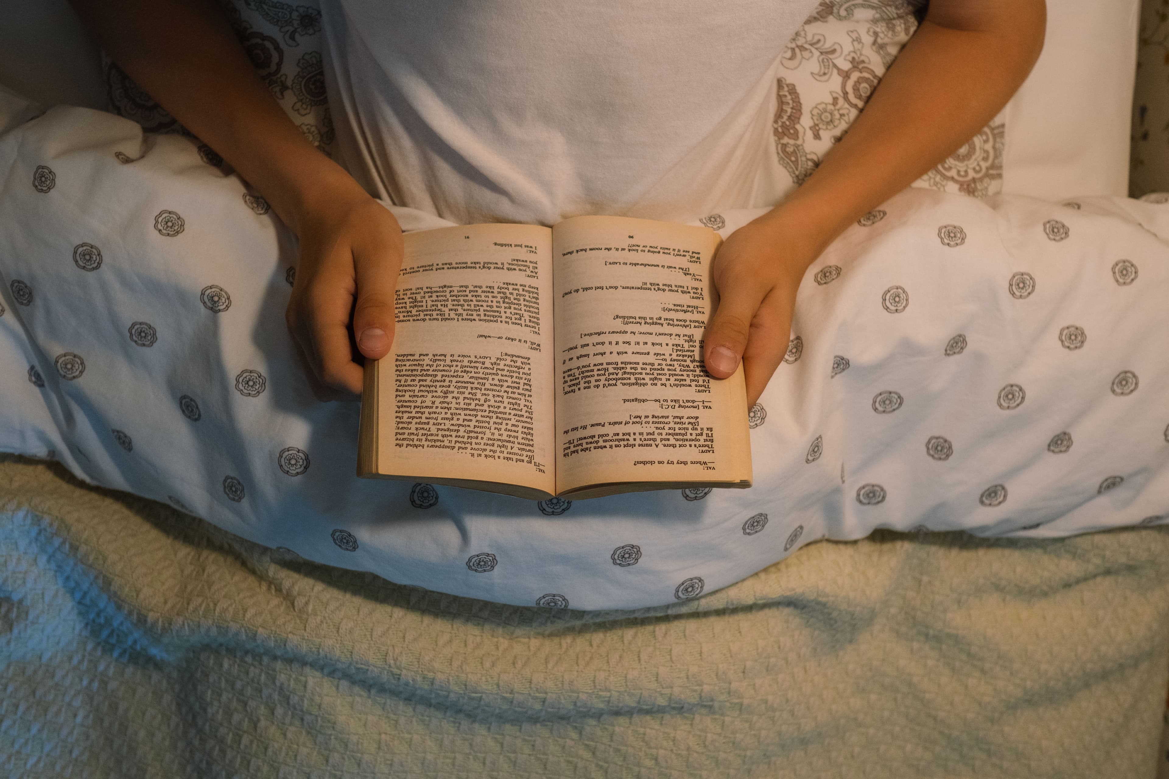 Person reading a book under warm light in the evening